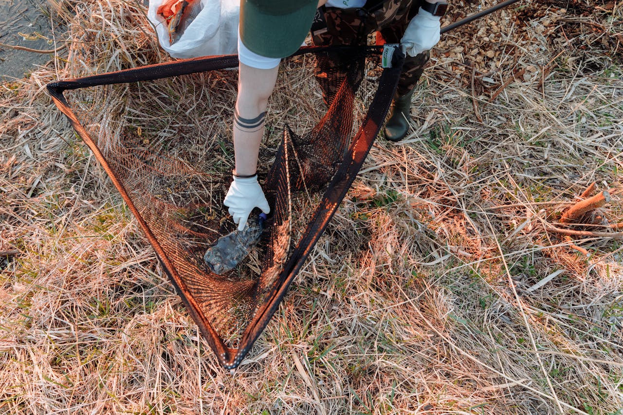 A volunteer cleaning up litter in a grassy area, promoting environmental conservation.